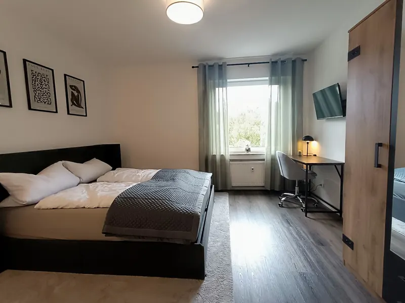 Schlafzimmer mit Doppelbett, Schreibtisch und TV