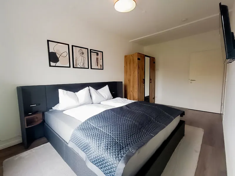 Schlafzimmer mit großem Polsterbett und Eichenschrank